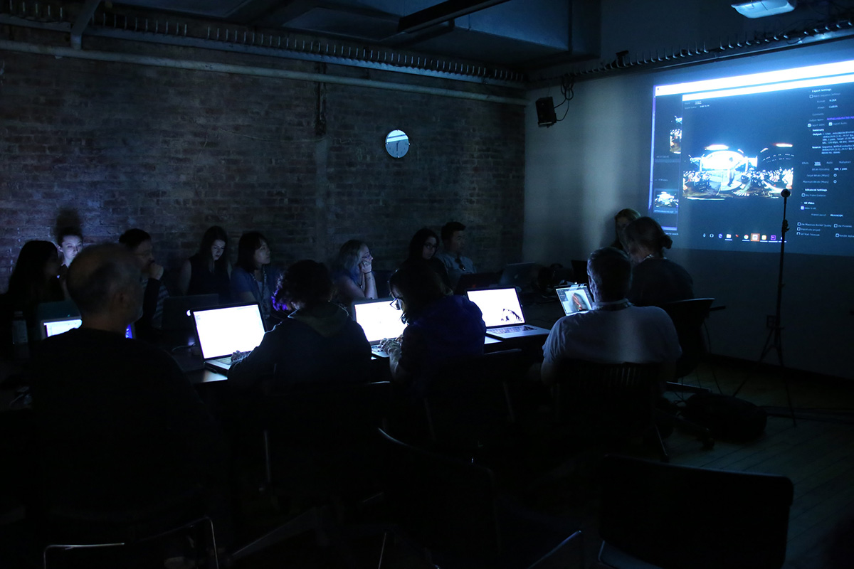 a lecture in a dark room with laptops illuminated